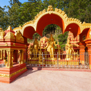 A vibrant photograph of the Seetha Amman Temple in Nuwara Eliya, Sri Lanka, with its colorful, intricately carved gopuram (tower) standing against a backdrop of green hills.